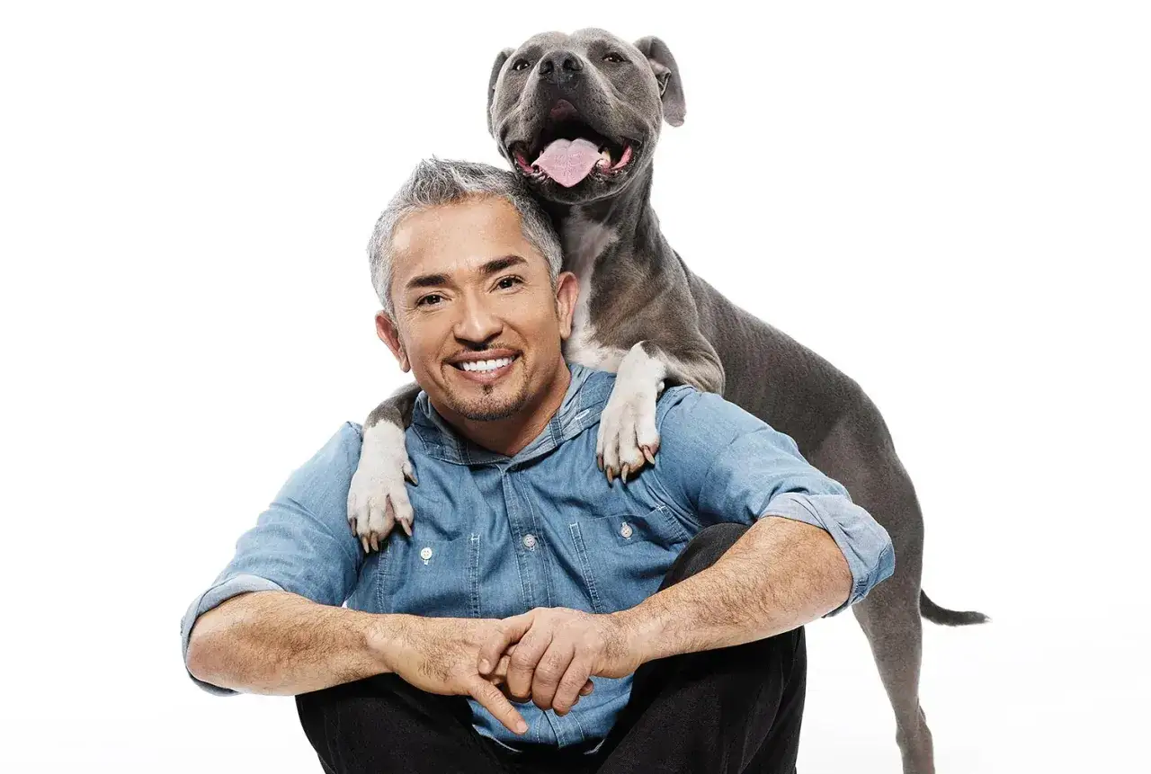 Cesar Millan, znany behawiorysta, z psem na ramionach.